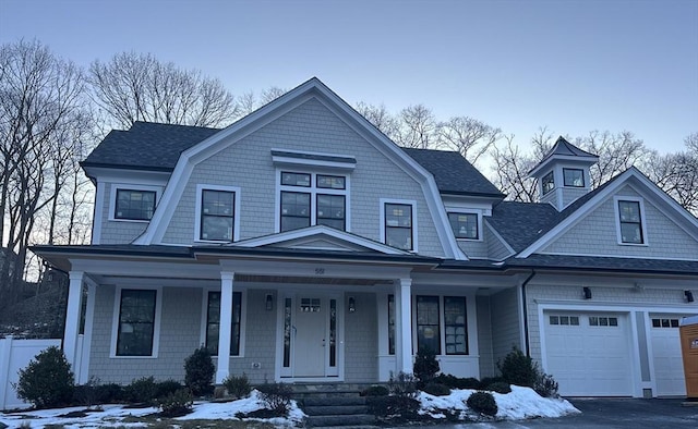 shingle-style home featuring a garage, a shingled roof, a porch, and a gambrel roof