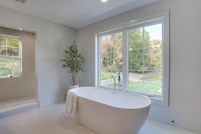 bathroom with a soaking tub, plenty of natural light, and baseboards