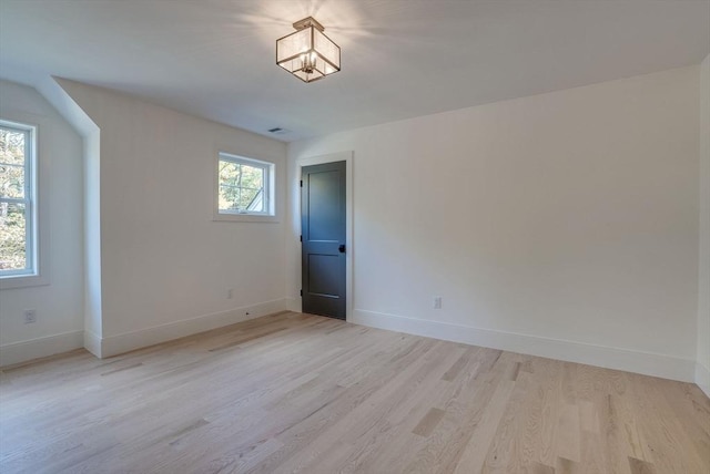 spare room with baseboards and light wood finished floors