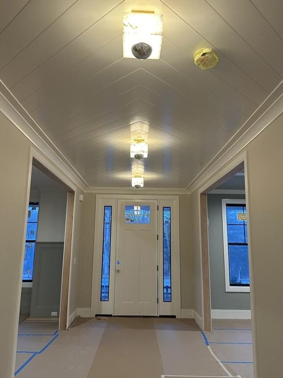 foyer featuring wood ceiling, crown molding, and baseboards