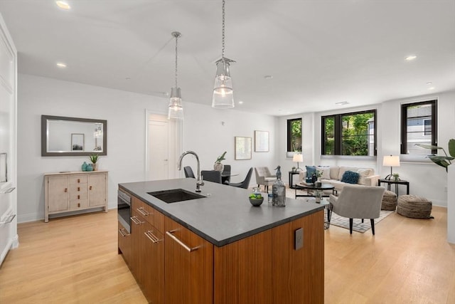 100 Linden St Unit 202, Wellesley, MA 02482 - kitchen with brown cabinets, dark countertops, light wood finished floors, an island with sink, and recessed lighting