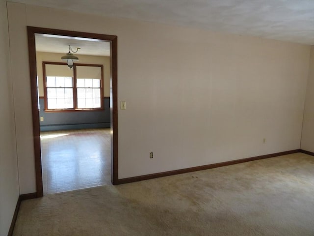 spare room with a baseboard radiator, baseboards, and carpet