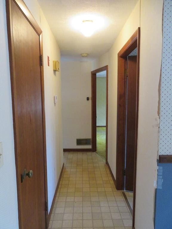 hallway featuring visible vents and baseboards