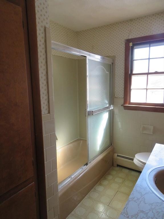 bathroom featuring wallpapered walls, bath / shower combo with glass door, wainscoting, tile walls, and a baseboard radiator