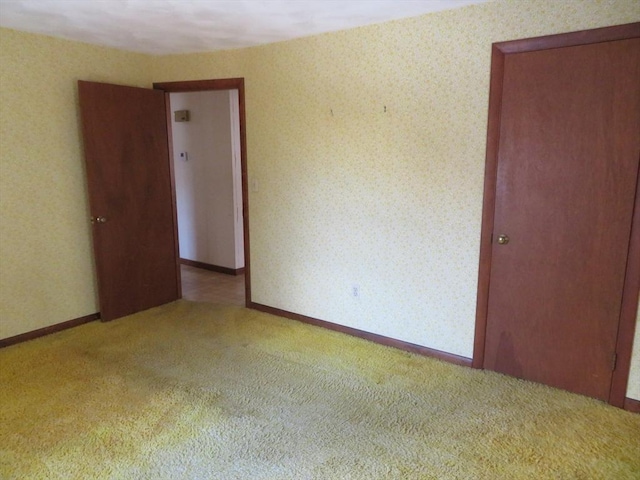 spare room featuring wallpapered walls, carpet flooring, and baseboards