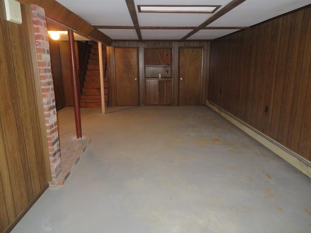 finished basement featuring a baseboard heating unit, wood walls, and stairs