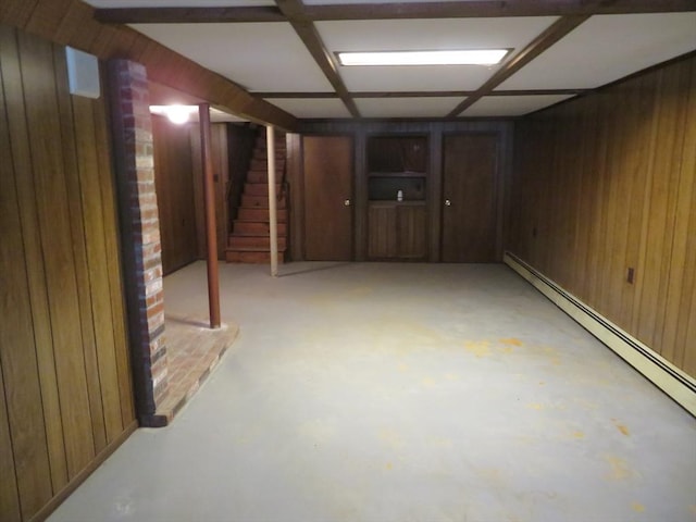 finished below grade area with wooden walls, stairway, and a baseboard heating unit