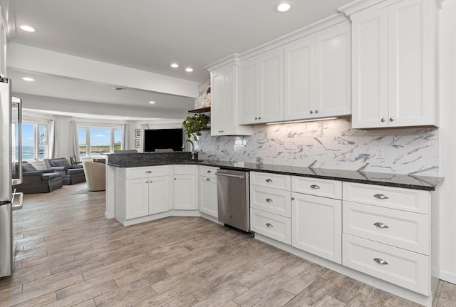 kitchen featuring white cabinetry, dark stone countertops, kitchen peninsula, and stainless steel appliances