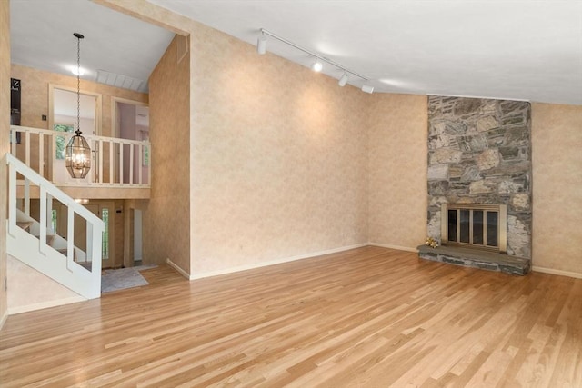 18 Juniper Ln, Framingham, MA 01701 - unfurnished living room featuring wood finished floors, track lighting, a chandelier, a fireplace, and stairway