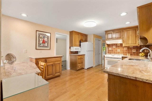 18 Juniper Ln, Framingham, MA 01701 - kitchen with white appliances, under cabinet range hood, tasteful backsplash, light stone counters, and light wood-style floors