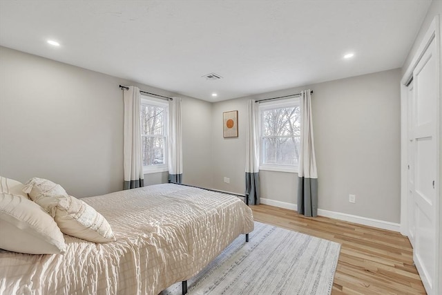 bedroom with multiple windows and light hardwood / wood-style flooring