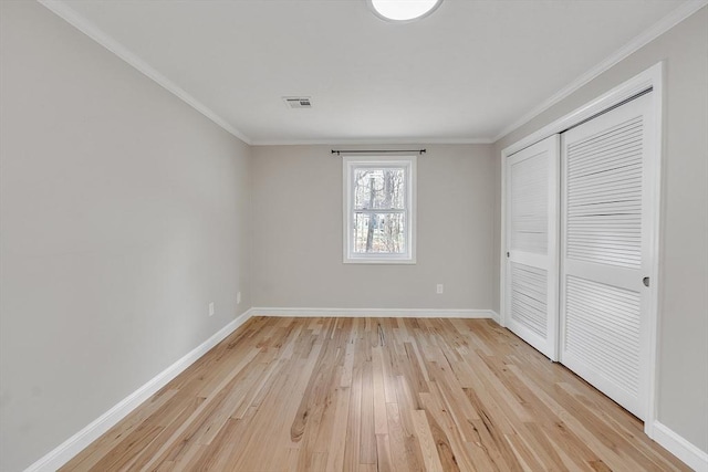 unfurnished bedroom featuring light hardwood / wood-style flooring, ornamental molding, and a closet