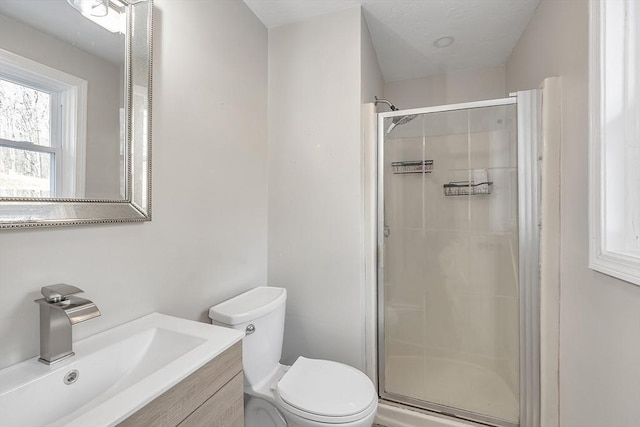 bathroom featuring vanity, a shower with shower door, and toilet