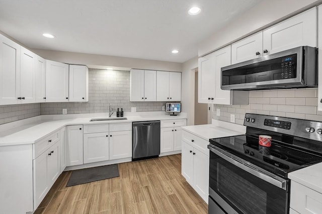 kitchen featuring white cabinetry, sink, light hardwood / wood-style flooring, and appliances with stainless steel finishes