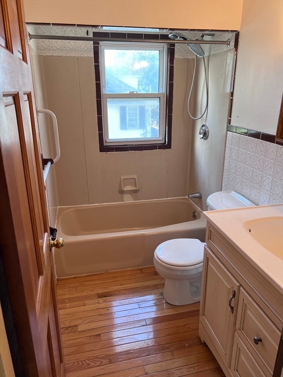 full bathroom featuring vanity, shower / tub combination, hardwood / wood-style flooring, tile walls, and toilet