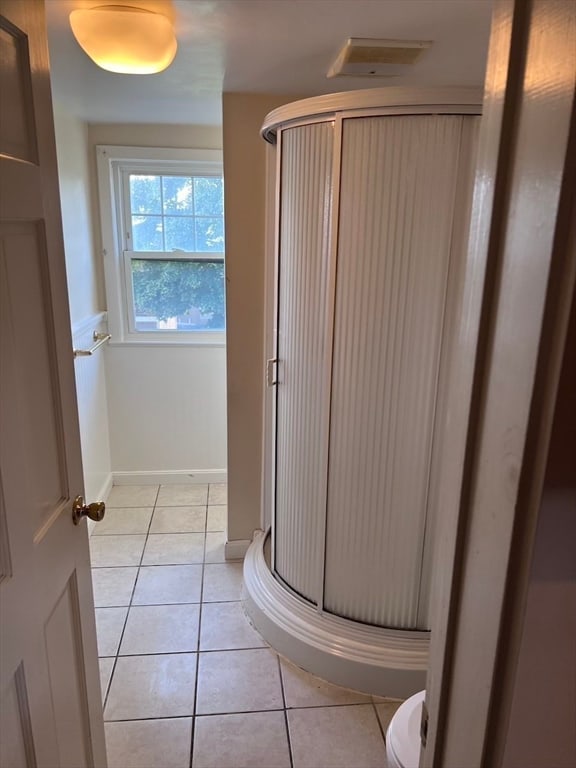 bathroom with toilet, an enclosed shower, and tile patterned floors