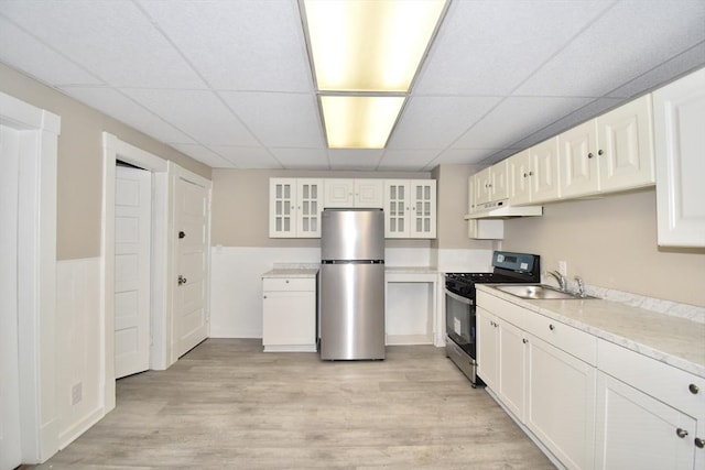 kitchen featuring a paneled ceiling, sink, light wood-type flooring, white cabinetry, and stainless steel appliances