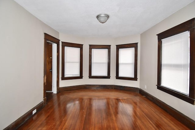 empty room with plenty of natural light and dark hardwood / wood-style flooring