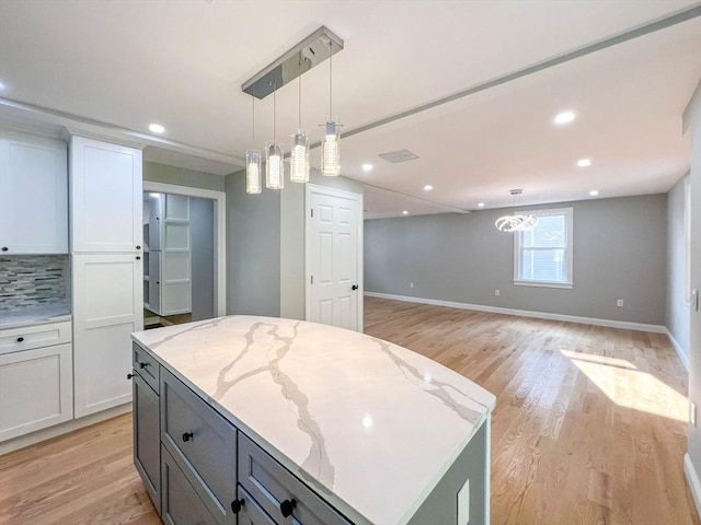 kitchen with light wood finished floors, white cabinetry, and decorative light fixtures