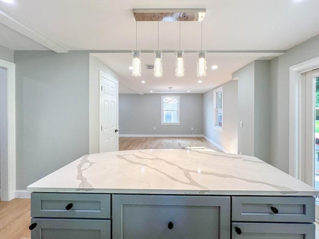 kitchen featuring light stone counters, gray cabinetry, and a center island