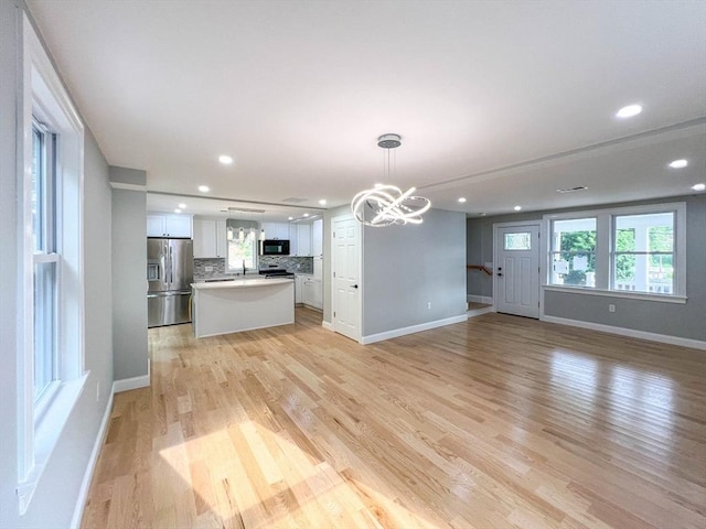 interior space with recessed lighting, baseboards, an inviting chandelier, and light wood finished floors