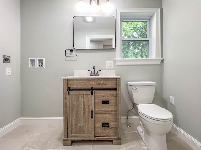 bathroom featuring baseboards, toilet, marble finish floor, and vanity