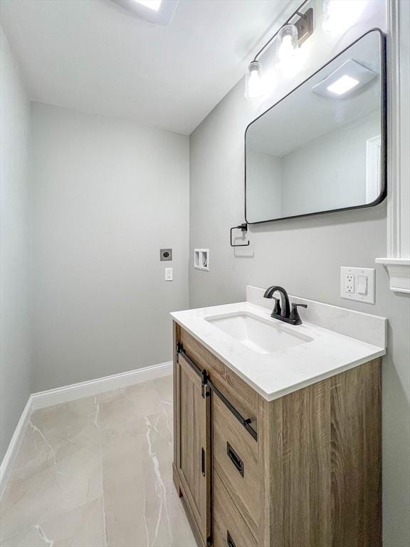 bathroom with marble finish floor, vanity, and baseboards