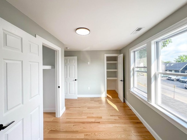 hallway with light wood-type flooring, baseboards, and visible vents