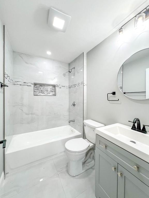 full bath featuring vanity, bathing tub / shower combination, toilet, and marble finish floor