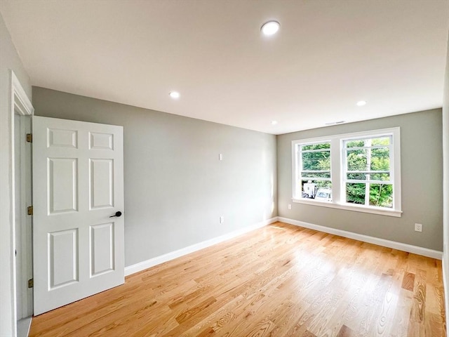 empty room featuring recessed lighting, baseboards, and light wood-type flooring