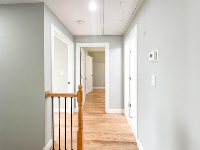 hallway with attic access, light wood-style floors, and baseboards