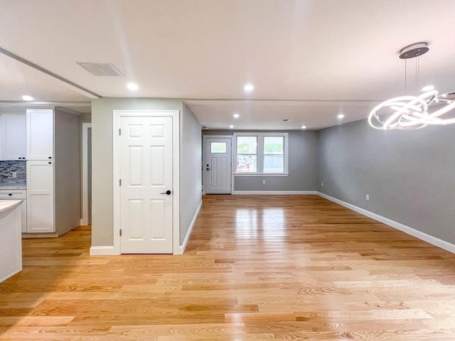 interior space featuring visible vents, baseboards, light wood-type flooring, recessed lighting, and an inviting chandelier