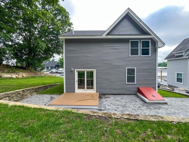 rear view of house with a deck, a patio area, and a lawn