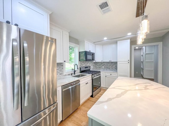 kitchen with tasteful backsplash, visible vents, appliances with stainless steel finishes, white cabinetry, and a sink