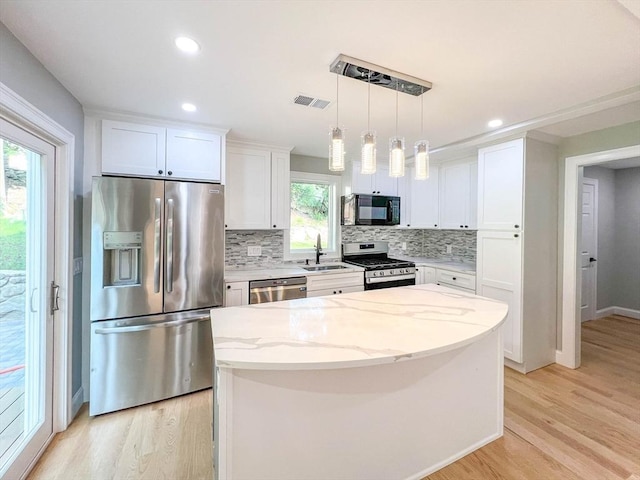 kitchen with light wood-type flooring, appliances with stainless steel finishes, and white cabinetry