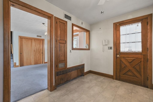 foyer entrance featuring light carpet and radiator heating unit