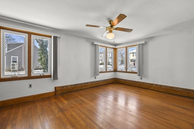 spare room featuring hardwood / wood-style flooring, a healthy amount of sunlight, and a baseboard heating unit