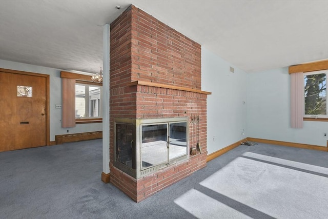 unfurnished living room with an inviting chandelier, a fireplace, and carpet flooring