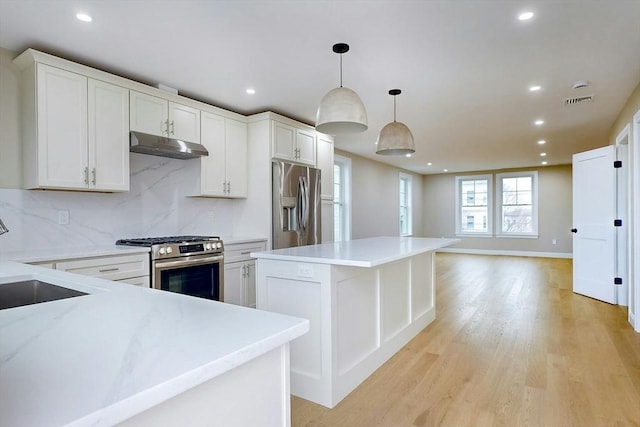 kitchen with backsplash, stainless steel appliances, white cabinetry, and hanging light fixtures