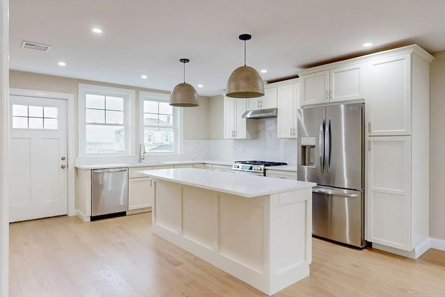 kitchen featuring appliances with stainless steel finishes, sink, pendant lighting, white cabinets, and a center island