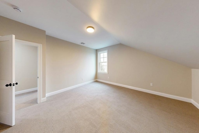 additional living space featuring light carpet and vaulted ceiling