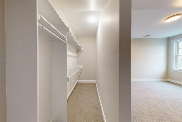 walk in closet featuring light colored carpet