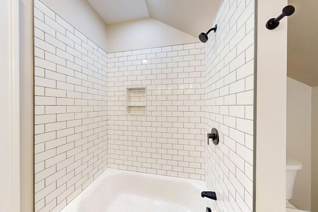 bathroom featuring tiled shower / bath combo and toilet