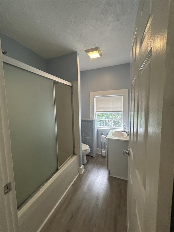36 Edwards St, Quincy, MA 02169 - full bathroom featuring wood finished floors, vanity, toilet, combined bath / shower with glass door, and a textured ceiling