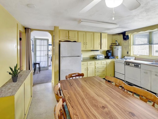 kitchen with white appliances, gas water heater, cream cabinets, a sink, and a ceiling fan