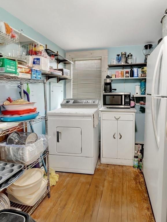 clothes washing area with washer / clothes dryer and light wood-style flooring