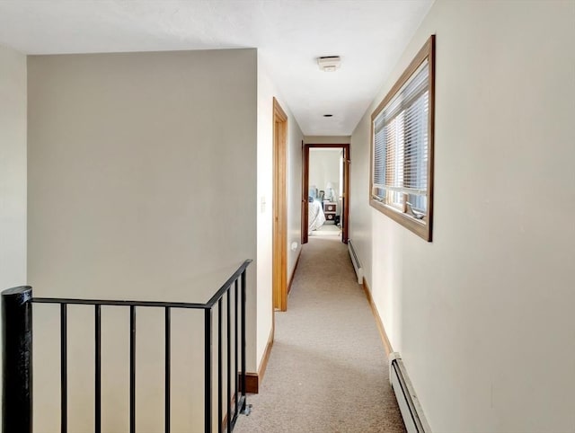 corridor featuring light colored carpet, a baseboard radiator, and baseboards