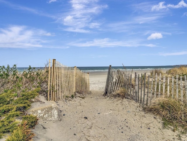 view of yard featuring view of water and beach and fence