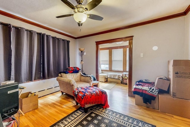 living area featuring wood finished floors, a ceiling fan, crown molding, and baseboard heating