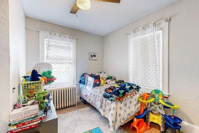 carpeted bedroom with ceiling fan and radiator heating unit